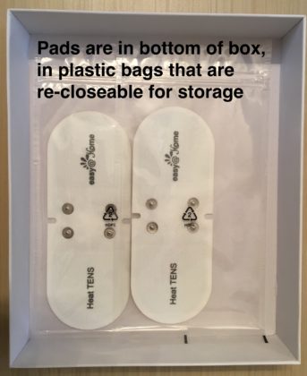 The bottom of a TENS machine box with pads in it. It is captioned "Pads are in bottom of box in plastic bags that are re-closeable for storage."