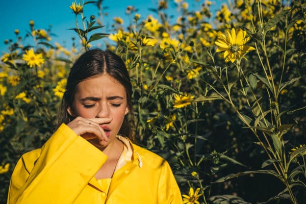 Throat Pain and Headaches woman sneezing with sinus infection