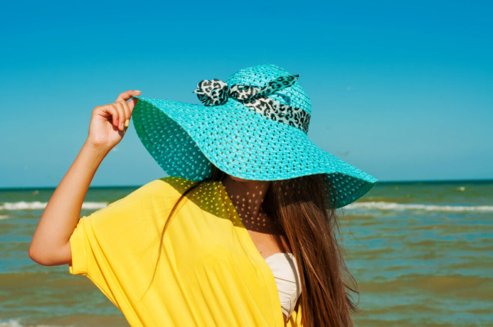 protect your skin from sunburn woman wearing wide brimmed hat on beach