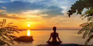 Woman meditating on the beach sunset